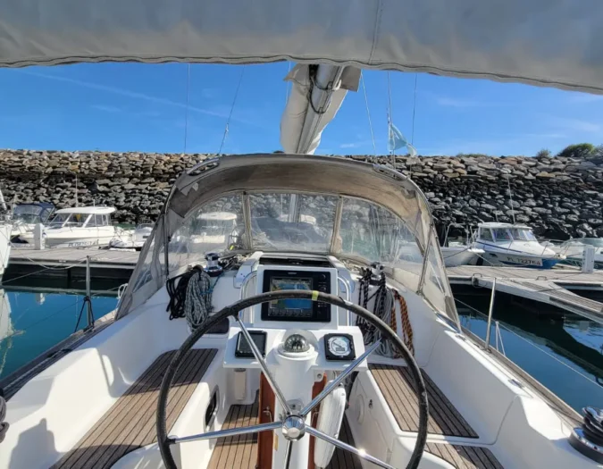 Un voilier de type Oceanis 31 DL avec un poste de pilotage spacieux et équipé d'un GPS traceur directement à la barre à roue.