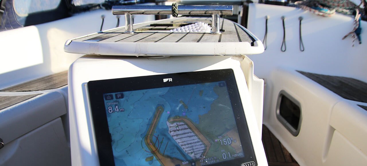 GPS marin sur un bateau monté sur une console blanche avec vue sur le port de Saint Quay Portrieux.