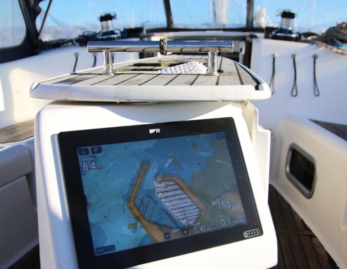 GPS marin sur un bateau monté sur une console blanche avec vue sur le port de Saint Quay Portrieux.