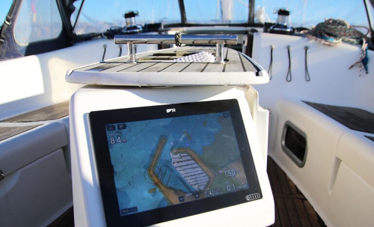 GPS marin sur un bateau monté sur une console blanche avec vue sur le port de Saint Quay Portrieux.
