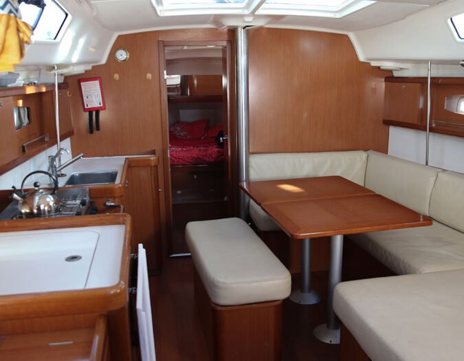 L'intérieur d'un oceanis 40 en location, vue sur le carré, 8 places autour de la table à manger. La table se descend pour une couchette 2 personnes.