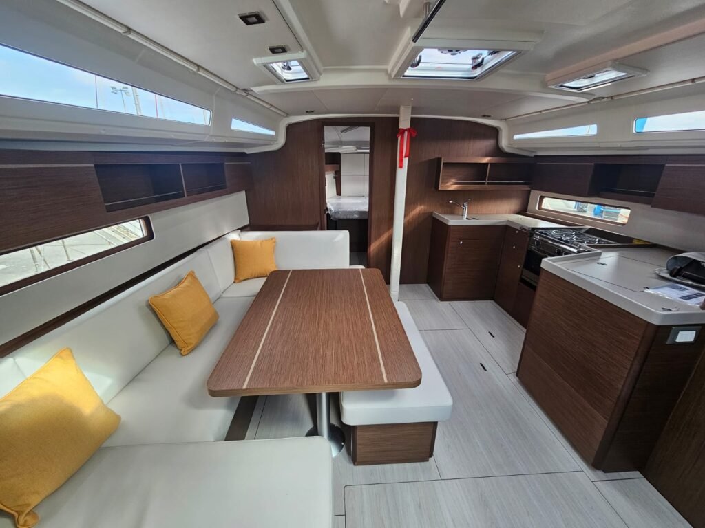 Espace de vie à bord d'un voilier de croisière de location. Espace repas et cuisine tout équipée.