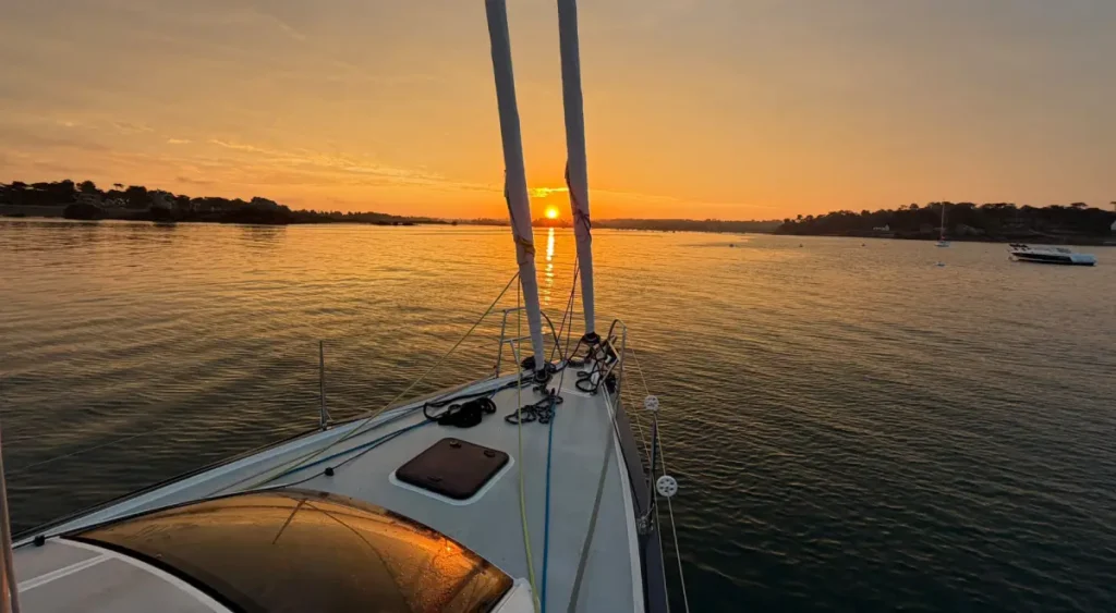 Coucher de soleil depuis la plage avant d’un voilier au mouillage à Port-Blanc, entre les îles