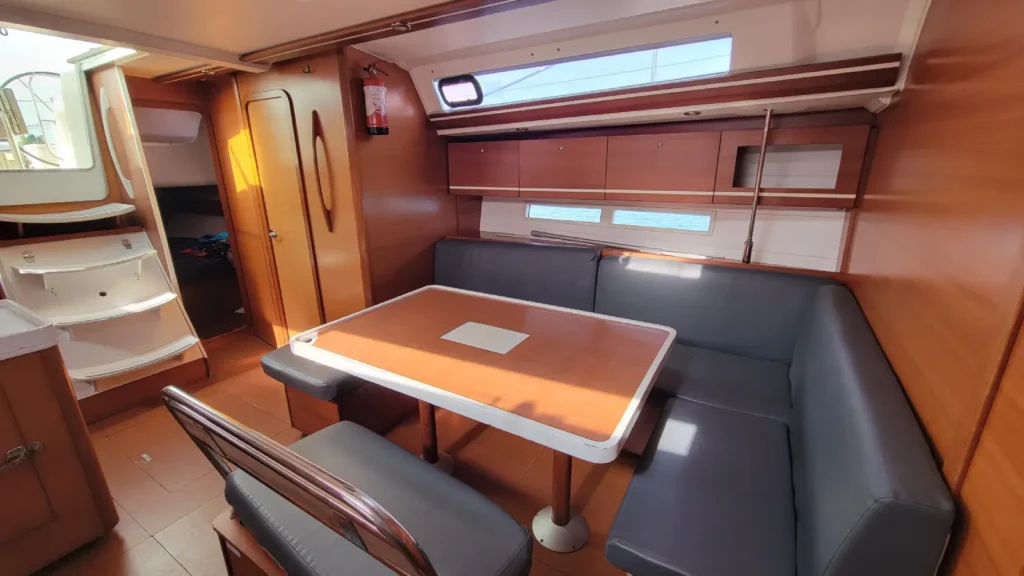 Espace repas du carré d'un voilier de location entre amis en Bretagne Nord, avec table et banquette